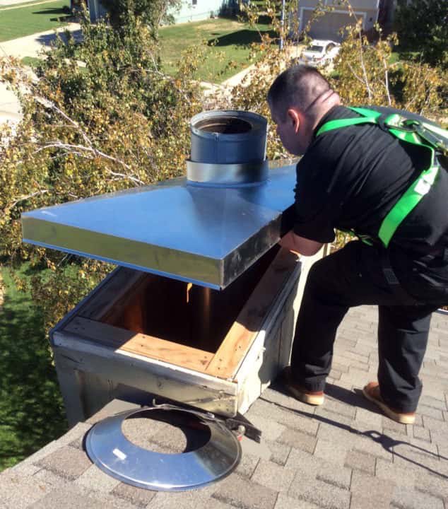 A worker on a roof installing a new chimney cap as part of a service by The Texan Chimney Sweep San Antonio, TX.