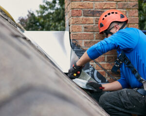 A worker installing new flashing around a brick chimney on a roof for Full Service Chimney in Overland Park, KS