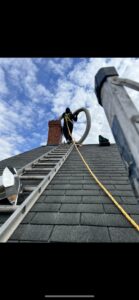 A worker on a roof installing a flexible chimney liner for Maximum Energy Savers in Philadelphia, PA