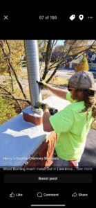 A worker on a roof installing a flexible chimney liner into a brick chimney, performed by Harry's Quality Chimney Services in Kansas City, MO