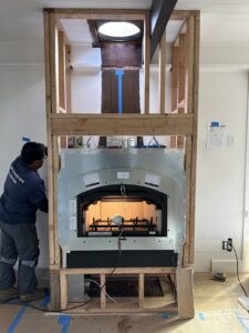 A worker from The Chimney Guy installing a new fireplace insert and liner in a home in Los Angeles, CA.