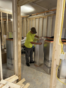 A worker installing insulated HVAC ductwork in a new construction project by HP Mechanical LLC in Santa Rosa, CA.
