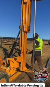A worker using heavy equipment to install a metal fence post for Julien Affordable Fencing LLC in Jacksonville, FL