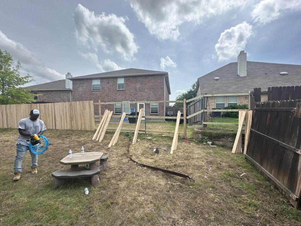 A worker installing a new wood fence in a residential backyard, demonstrating the services of NTX-Exterior Services in Dallas, TX.