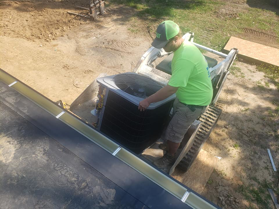 A worker installing an outdoor HVAC condenser unit with heavy equipment for Kopetsky HVAC in Indianapolis, IN.