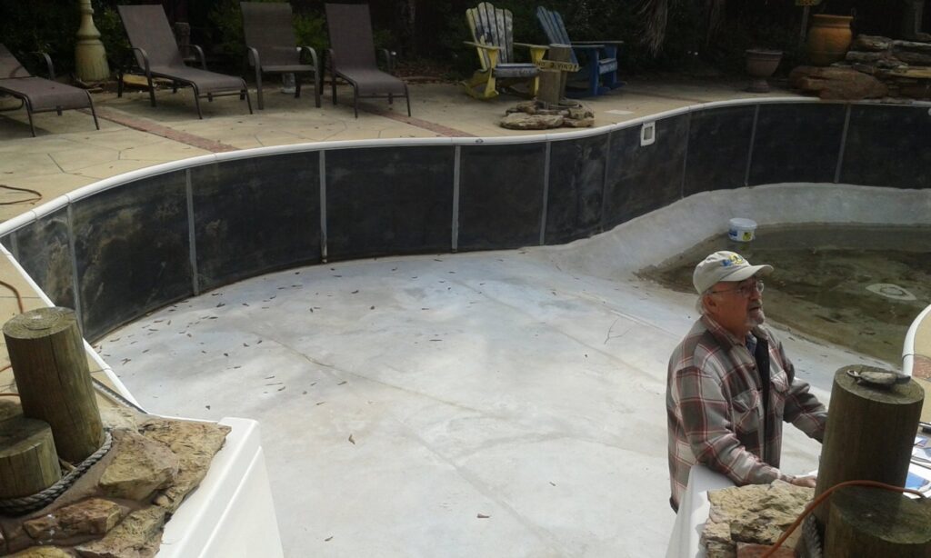 A worker standing in an empty pool with liner panels installed on the walls, showing service by Brian's Pool Service in Baton Rouge, LA.