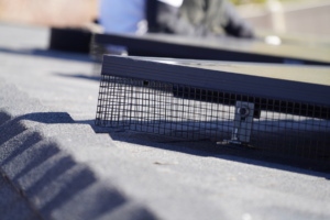 A worker installing protective bird guards around solar panels on a roof by Bell Mountain Solar Panel Bird Guards in Orem, UT