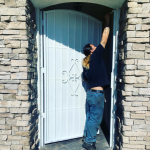 A worker installing a white metal security gate, demonstrating the services of Portugal's IronWorks in Los Angeles, CA.