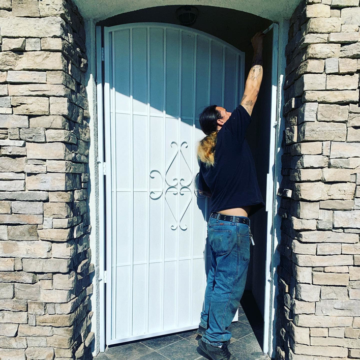A worker installing a white metal security gate, demonstrating the services of Portugal's IronWorks in Los Angeles, CA.