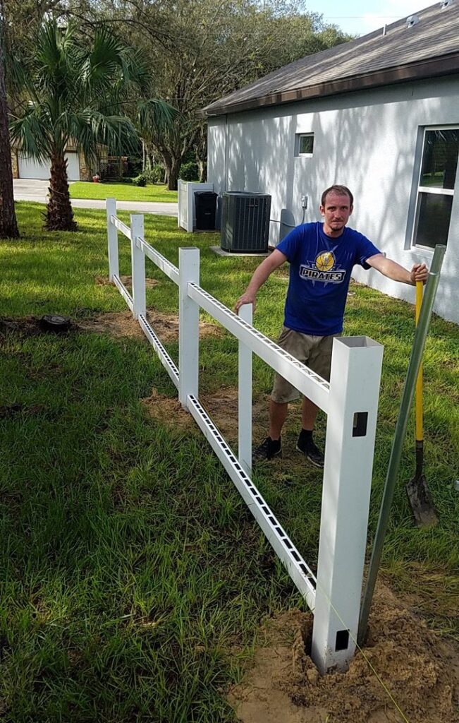 A worker installing a section of white vinyl fence, showing the construction process by Aarons fence in Homosassa Springs, FL