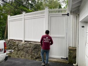 A worker installing a white vinyl privacy fence and gate for RP Fencing & Gates in Brewster, NY