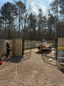 A worker installing a new wooden fence and gate for a residential property by JBunlimitedfencingllc in Savannah, GA.