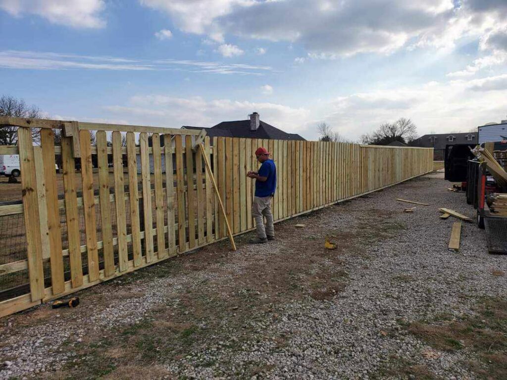 A worker installing wood fence pickets for a new fence project by Straight Shot Solutions, LLC in Fort Worth, TX.