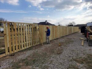 A worker installing wood fence pickets for a new fence project by Straight Shot Solutions, LLC in Fort Worth, TX.