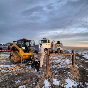 A worker using a skid steer with an auger to install wood fence posts for Life Time Fence, Inc. in Cedar Rapids, IA.