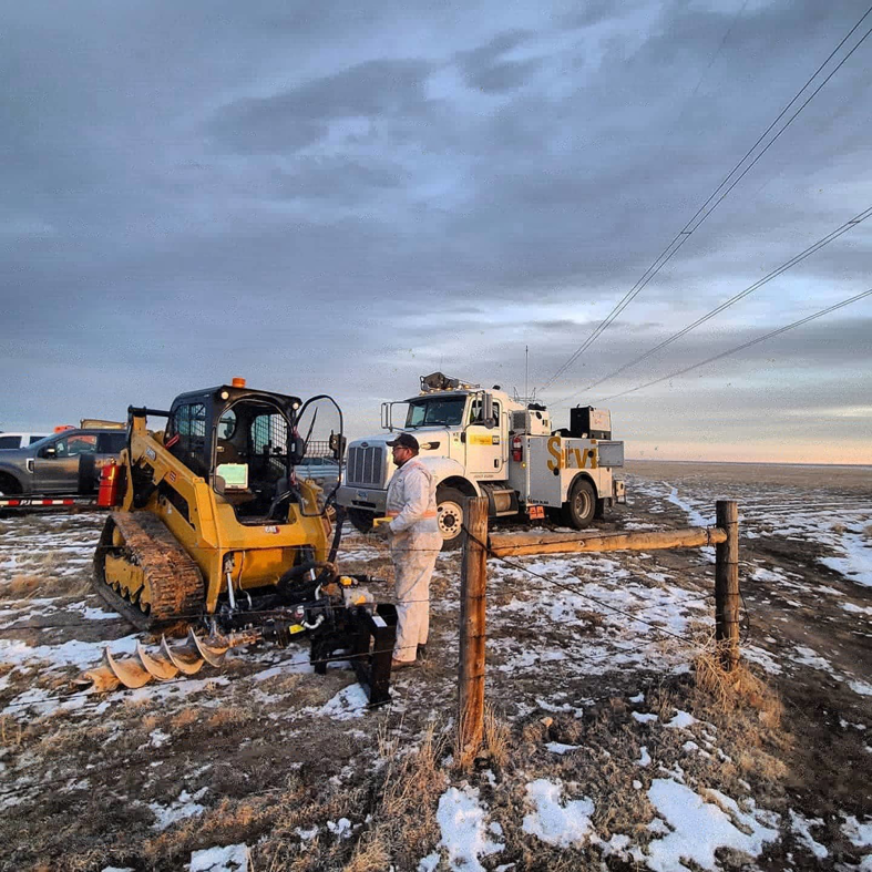 A worker using a skid steer with an auger to install wood fence posts for Life Time Fence, Inc. in Cedar Rapids, IA.