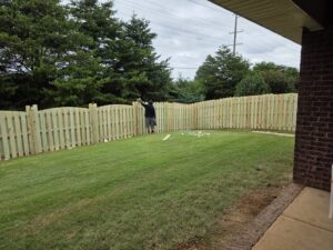 A worker installing a new wood picket fence in a residential backyard for Alabama's Fencing in Huntsville, AL.