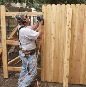 A worker using a nail gun to install wooden pickets for a new privacy fence by Julien Affordable Fencing LLC in Jacksonville, FL