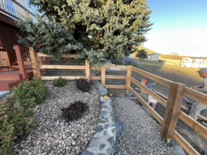 A worker installing a wood and wire mesh fence for Denfence Team in Colorado Springs, CO
