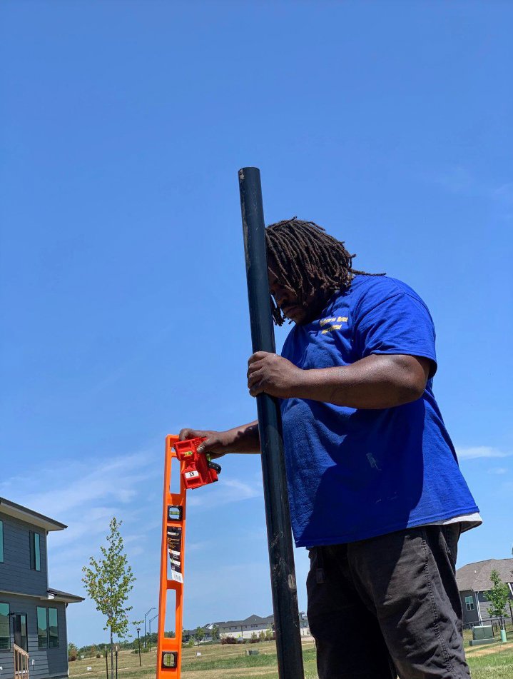 A worker from Stallworth Home Improvement leveling a fence post during installation in Des Moines, IA.