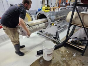 A worker loading a rolled-up area rug into a large automatic cleaning machine at Personal Touch Carpet Cleaning in Chicago, IL.