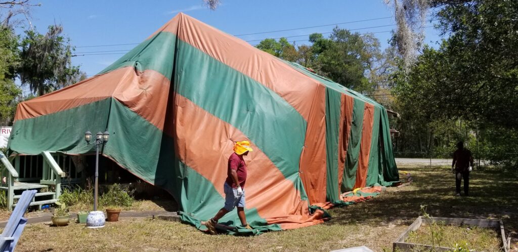 A worker walking near a residential house covered in a fumigation tent by Rivers Pest Control Service, Inc. in Jacksonville, FL