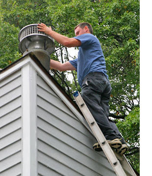 A worker on a ladder installing a chimney cap on a roof for The Texan Chimney Sweep San Antonio, TX.