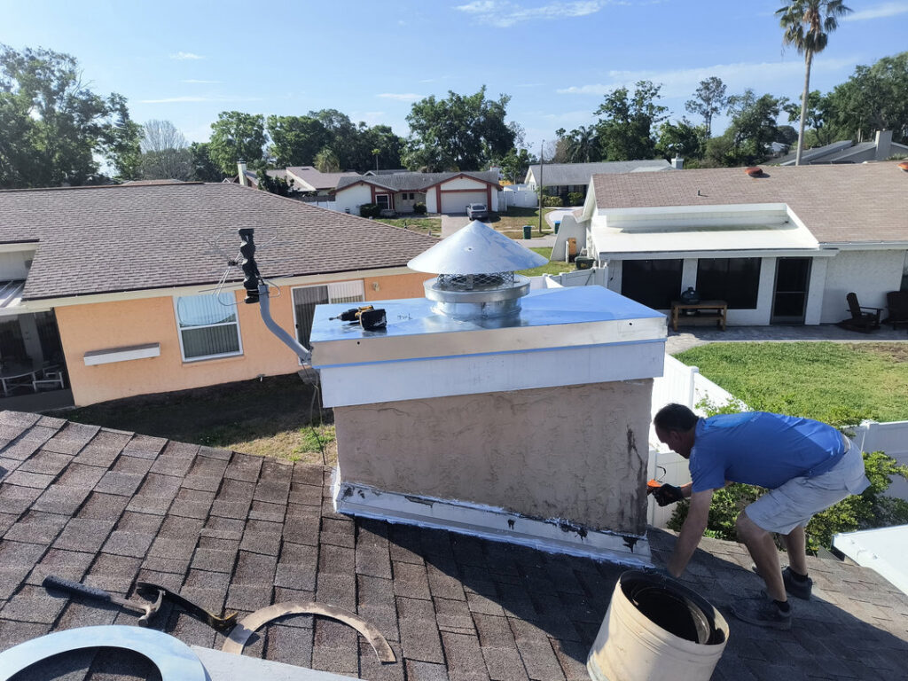 A worker on a roof repairing chimney flashing or applying sealant, performed by A Sweep Across the Bay in Parrish, FL.