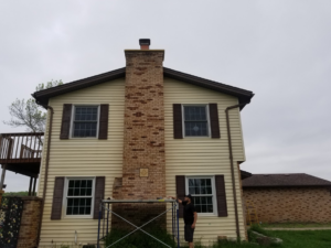 A worker on scaffolding performing repair or maintenance on a brick chimney for Proto Chimney Services in Stillwater, MN.
