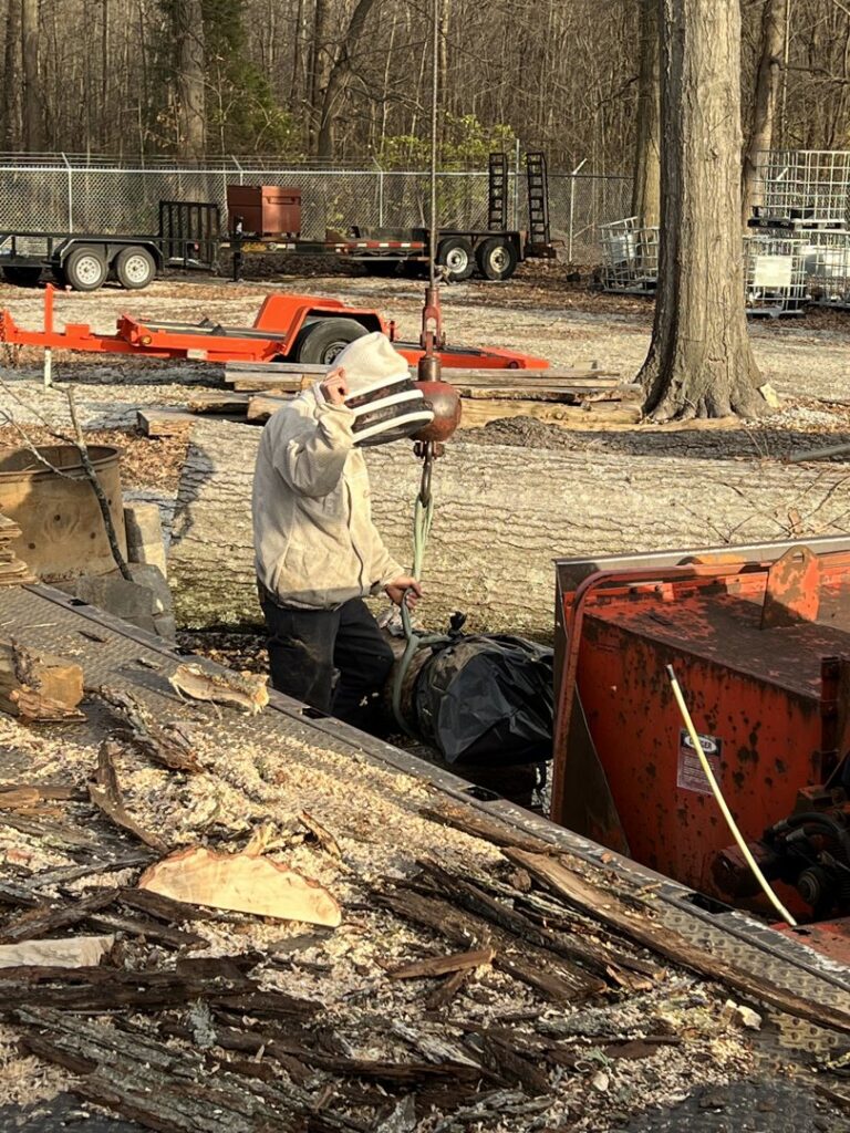 A worker operating a wood chipper at a tree removal site for Peek Lawn Care LLC in Windy Hills, KY.