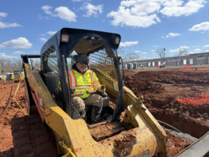 A worker operating a skid steer loader for geothermal ground loop installation at Jackson Geothermal in Mansfield, OH.
