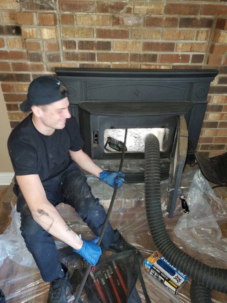 A worker performing an interior chimney sweep with tools and a vacuum hose by Clean Sweep Chimney Service in Saint Charles, MO.