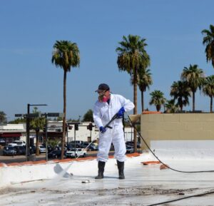 A worker in protective gear power washing bird droppings from a rooftop, a service offered by Pigeon Control Phoenix AZ in Glendale, AZ.