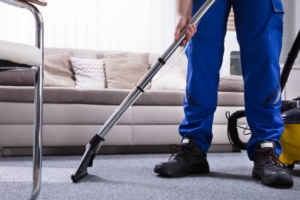A worker in uniform using professional carpet cleaning equipment on a grey carpet for Spears Americare in Hopkinsville, KY.