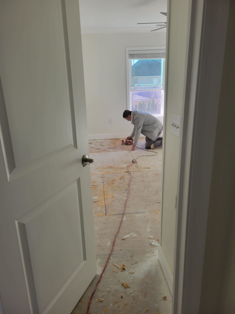 A worker removing old carpet and preparing the subfloor for new installation by Santos Floors & Tile in Frederick, MD.