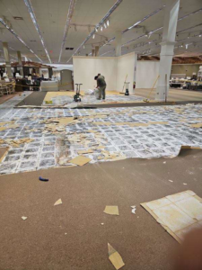 A worker removing old carpet and cleaning debris in a commercial space by Universal Flooring LLC in Las Cruces, NM