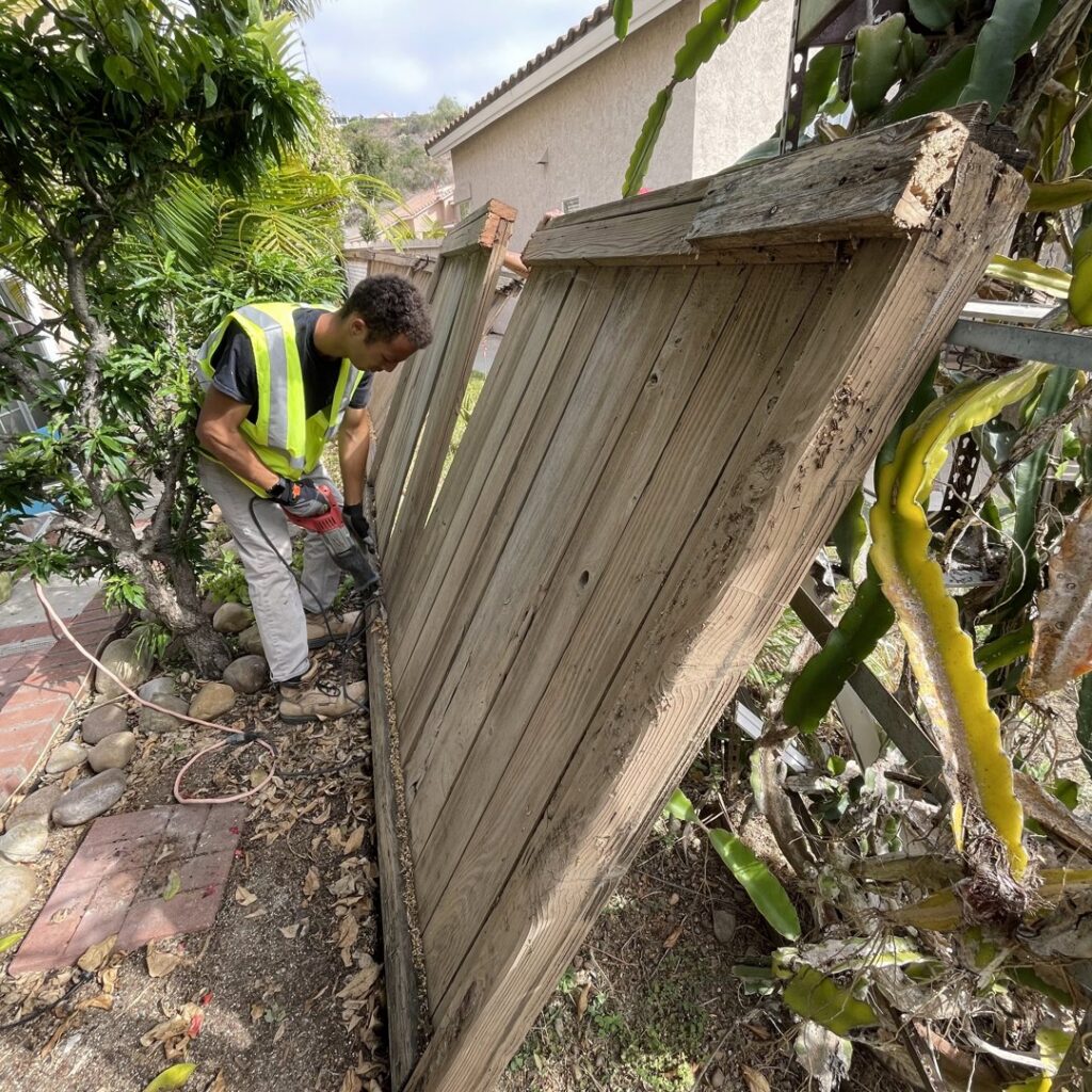 A worker removing an old wooden fence section, part of a fencing project by San Diego Fencing Contractor A's Pro Build Fencing in San Diego, CA.