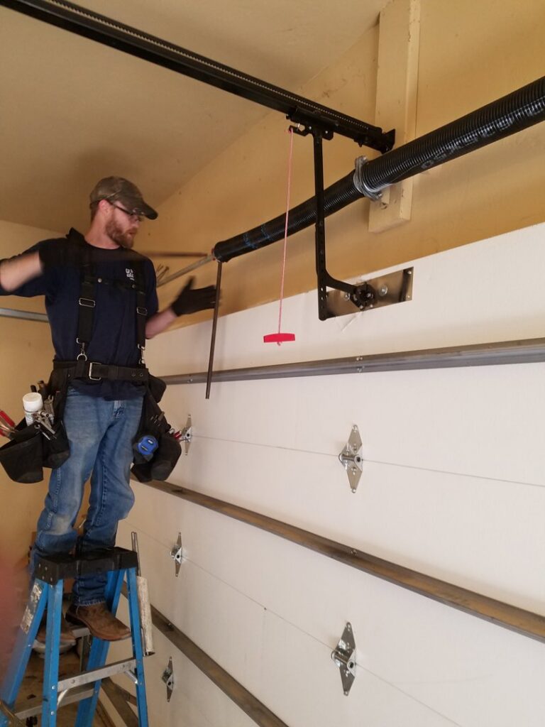 A worker repairing a garage door spring system for Garage Door Specialists Of Oklahoma Inc. in Oklahoma City, OK