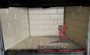 A Brushers Chimneys worker on a ladder repairing the siding of a chimney in Houston, TX.