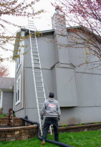A worker setting up a ladder to access a chimney for Full Service Chimney in Overland Park, KS