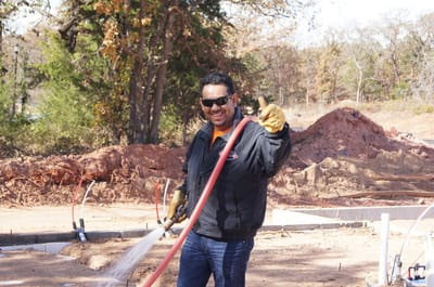 A Reliable Termite of OKC worker giving a thumbs up while spraying a new construction foundation in Oklahoma City, OK.
