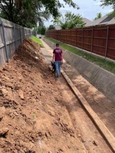 A worker in a trench during fence or retaining wall installation by DWM FENCE in Norman, OK