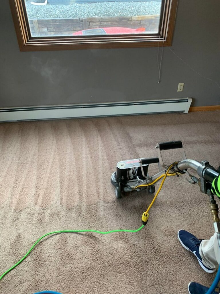 A worker operating a rotary carpet cleaning machine to deep clean carpet for Alaska Dry Carpet in Anchorage, AK.