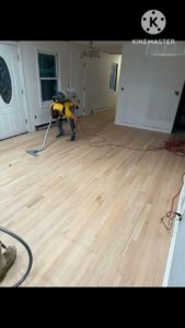 A worker vacuuming a newly installed hardwood floor as part of the finishing process by Isad Home Floor in Bridgeport, CT.