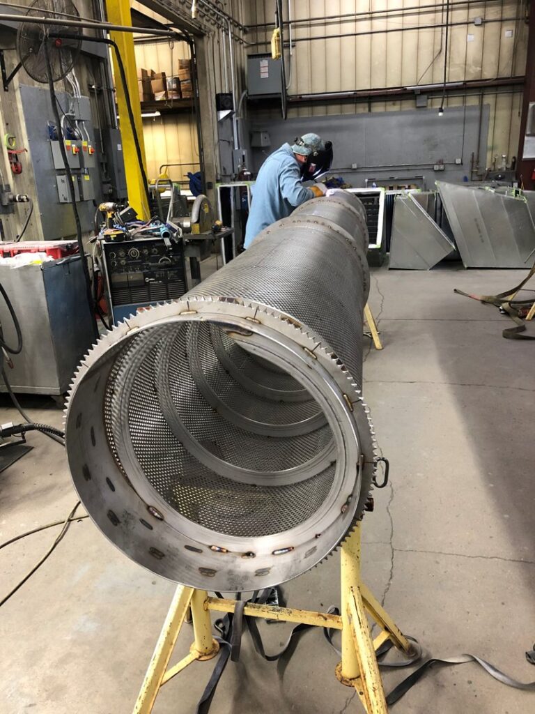 A worker welding a large custom HVAC duct component in the workshop at Central Consolidated in Wichita, KS