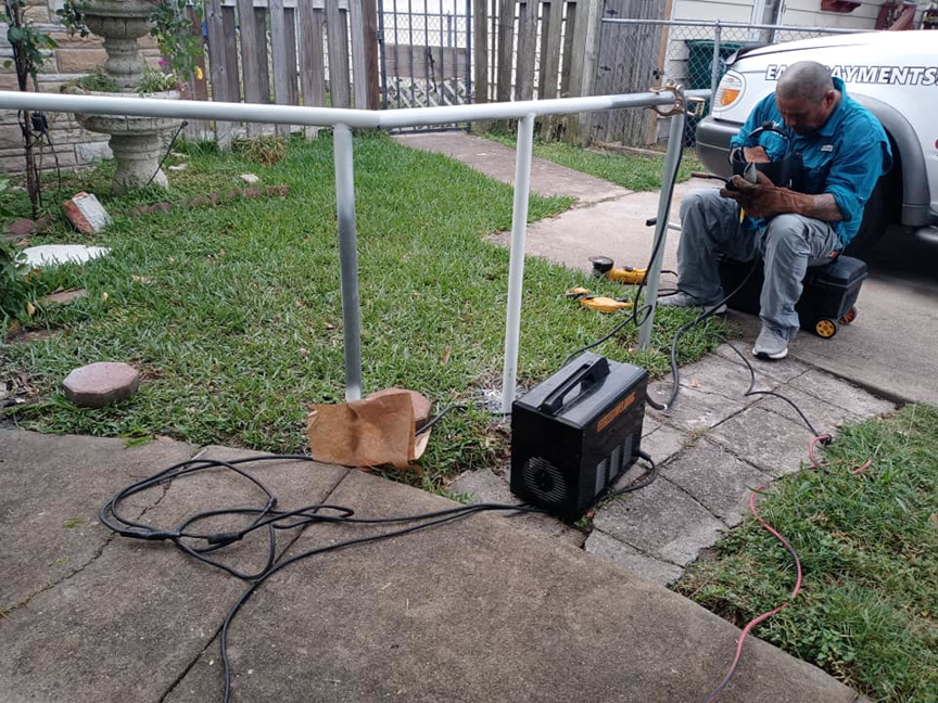 A worker welding an installed metal fence or railing for Morin Fencing in Corpus Christi, TX.