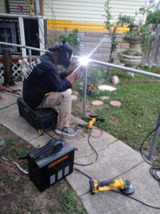 A worker welding a metal fence post during installation by Morin Fencing in Corpus Christi, TX.