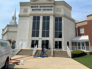 A worker setting up cleaning hoses outside a church building for Great Day Carpet & Tile Cleaning LLC Desoto in Olive Branch, MS.