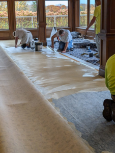 Workers applying adhesive to the floor for carpet installation by Craftmark Installations LLC in Broken Arrow, OK
