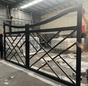 Workers assembling a large black metal gate in a workshop for All With Us LLC in Green Cove Springs, FL.